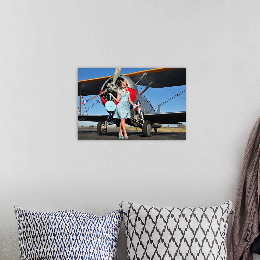 A bohemian room featuring Elegant 1940's style pin-up girl standing in front of an F3F biplane.