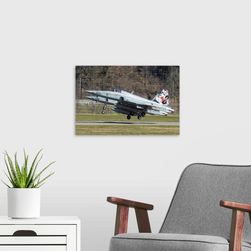 A modern room featuring F-5E Tiger II from the Swiss Air Force taking off.
