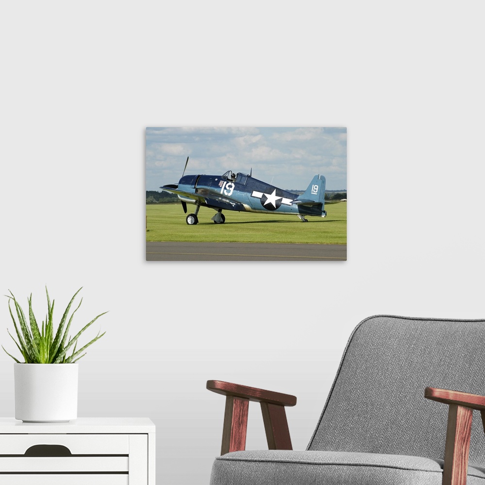 A modern room featuring Grumman F6F Hellcat in World War II U.S. Navy colors while taxiing at Duxford airport, England.