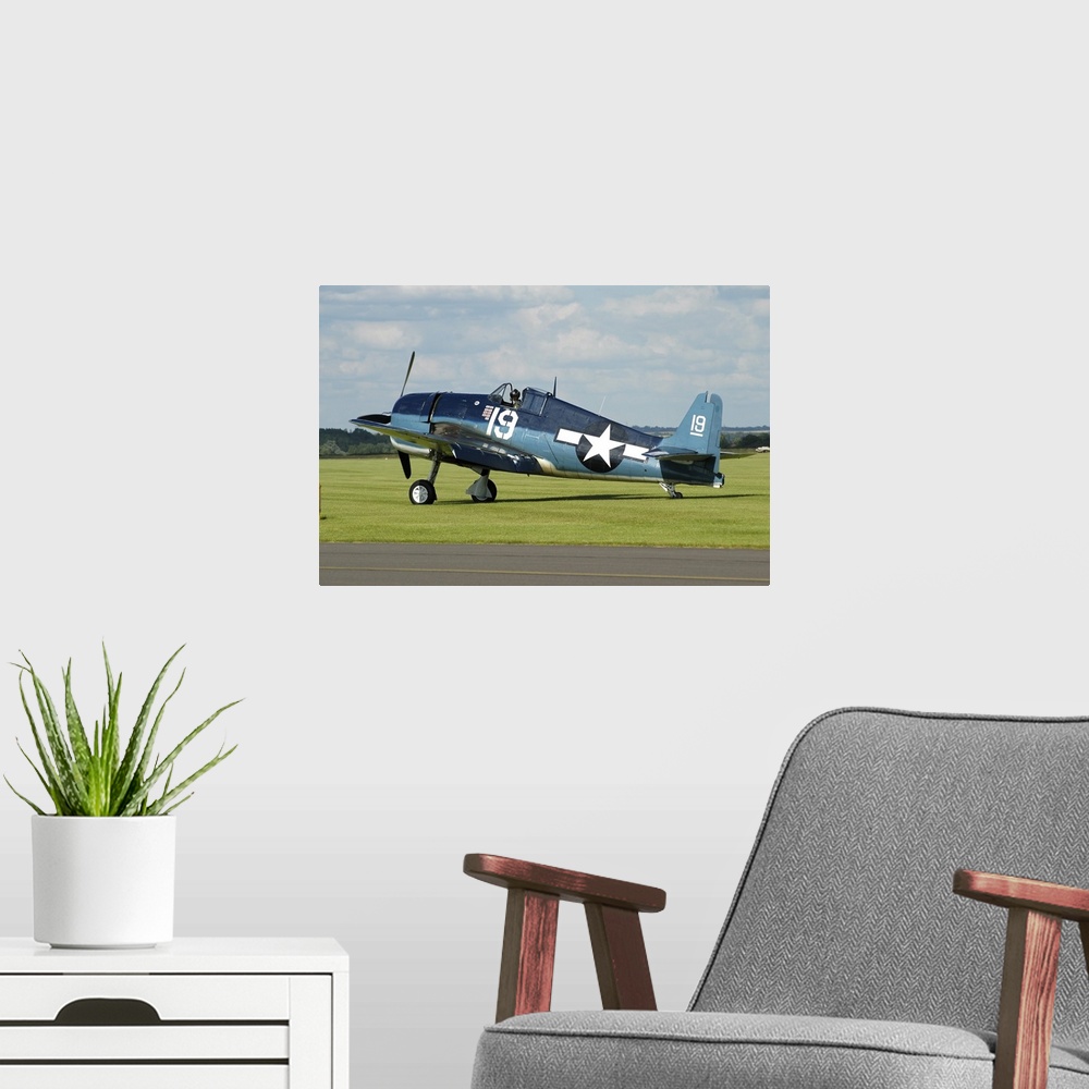 A modern room featuring Grumman F6F Hellcat in World War II U.S. Navy colors while taxiing at Duxford airport, England.