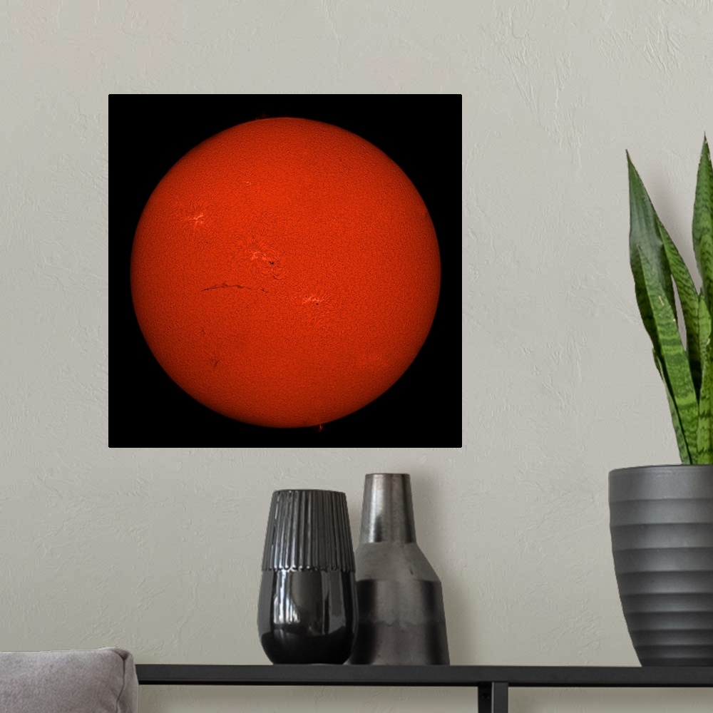 A modern room featuring H-alpha full Sun in red color with active areas and filaments.