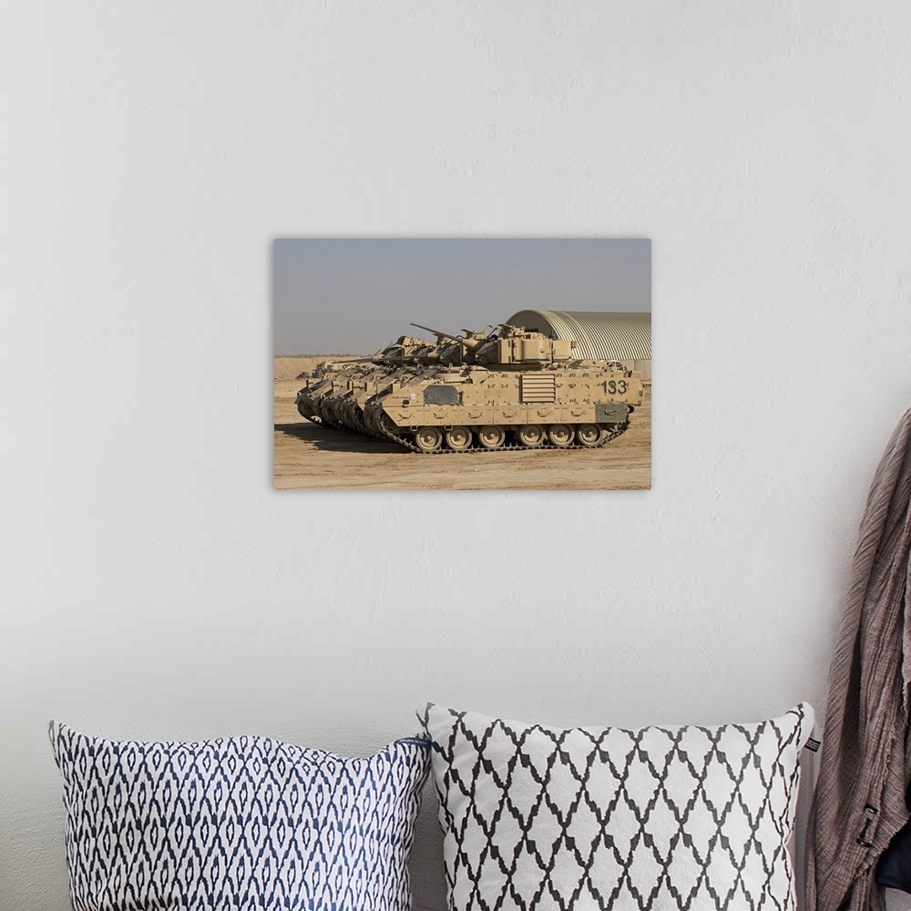 A bohemian room featuring Large landscape photograph of a line of M2/M3 Bradley Fighting Vehicles cruising over a dirt land...