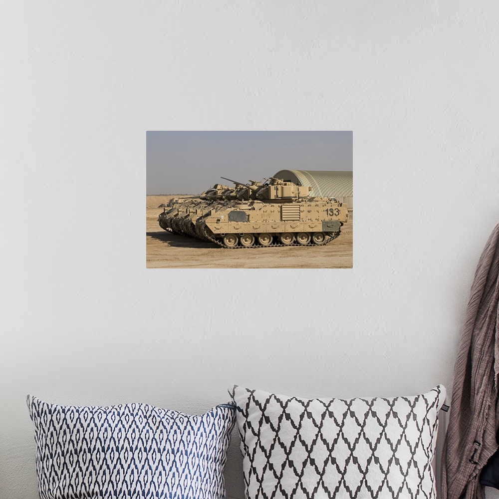 A bohemian room featuring Large landscape photograph of a line of M2/M3 Bradley Fighting Vehicles cruising over a dirt land...