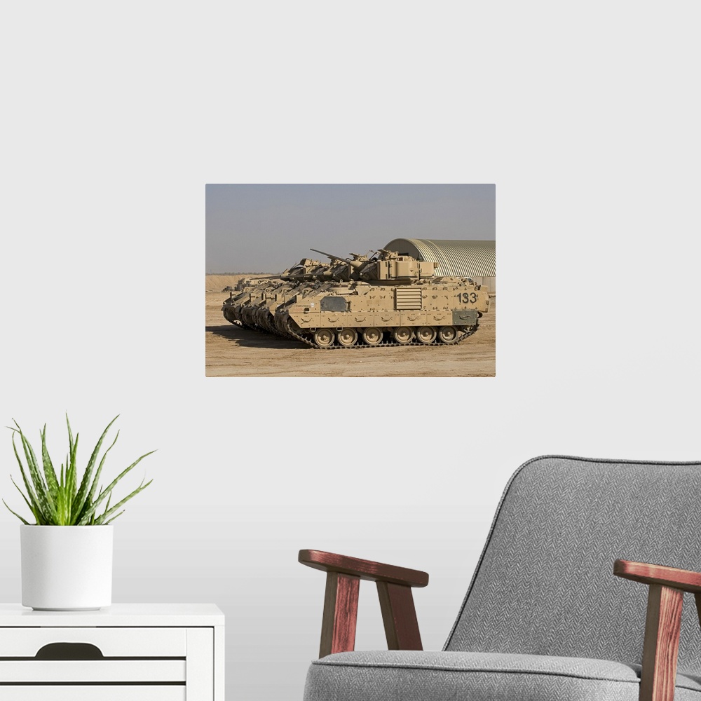 A modern room featuring Large landscape photograph of a line of M2/M3 Bradley Fighting Vehicles cruising over a dirt land...