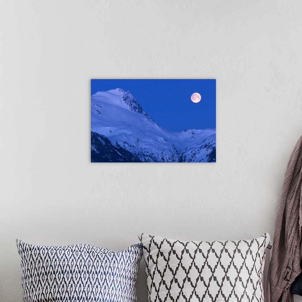 A bohemian room featuring Large image on canvas of a full moon to the right of a tall snowy mountain ridge.