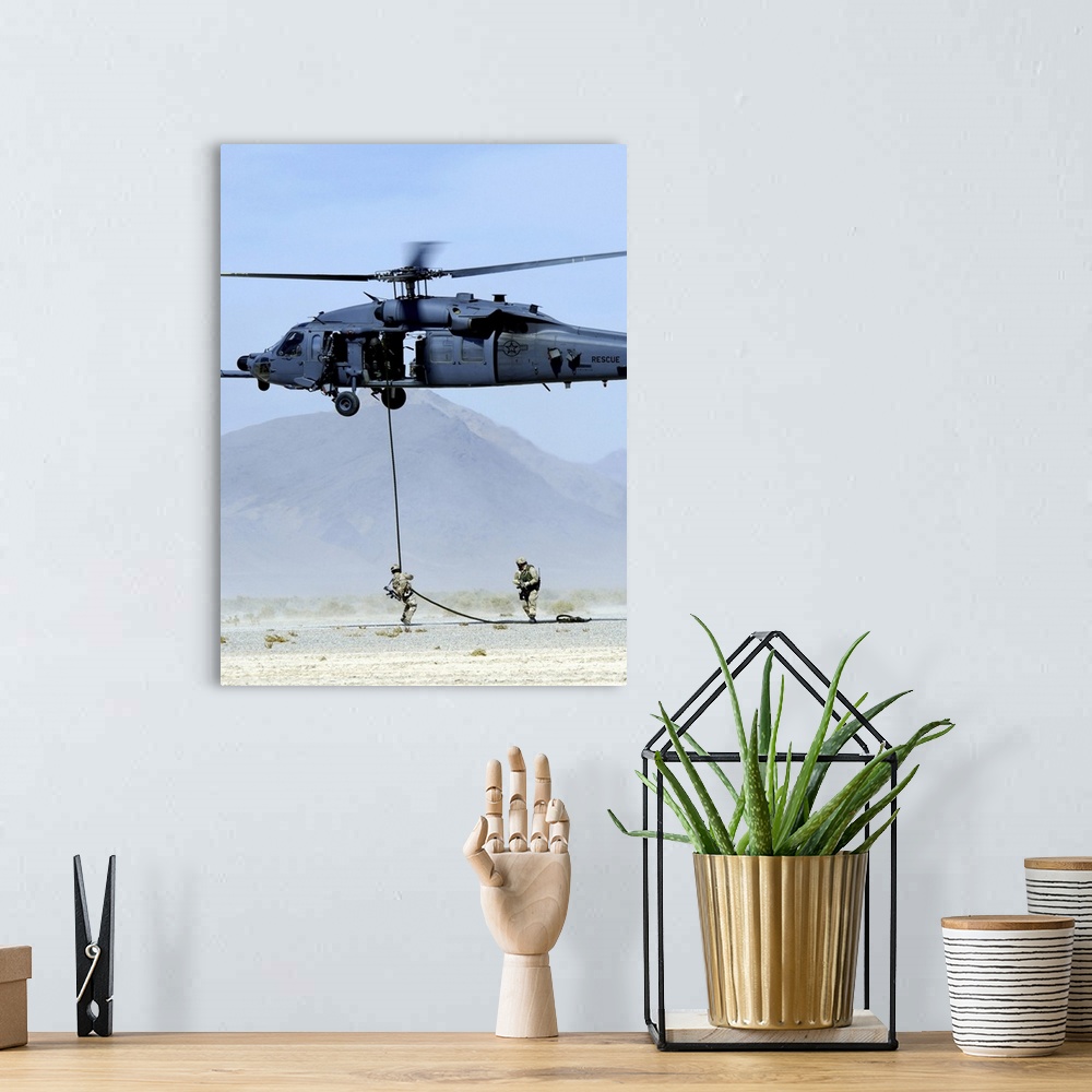 A bohemian room featuring Pararescuemen descend from an HH-60 Pave Hawk helicopter.