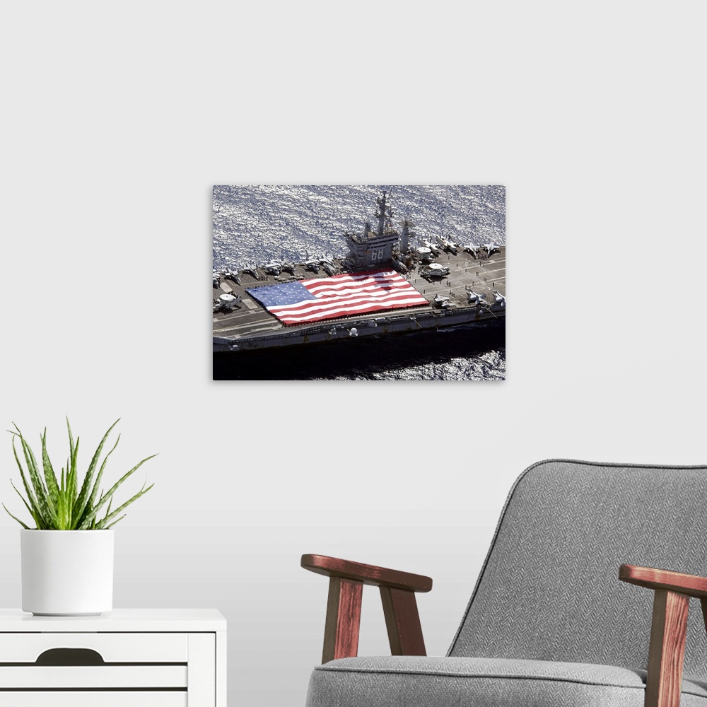 A modern room featuring Canvas print of a big American flag being held next to planes sitting on top of a huge navy ship.