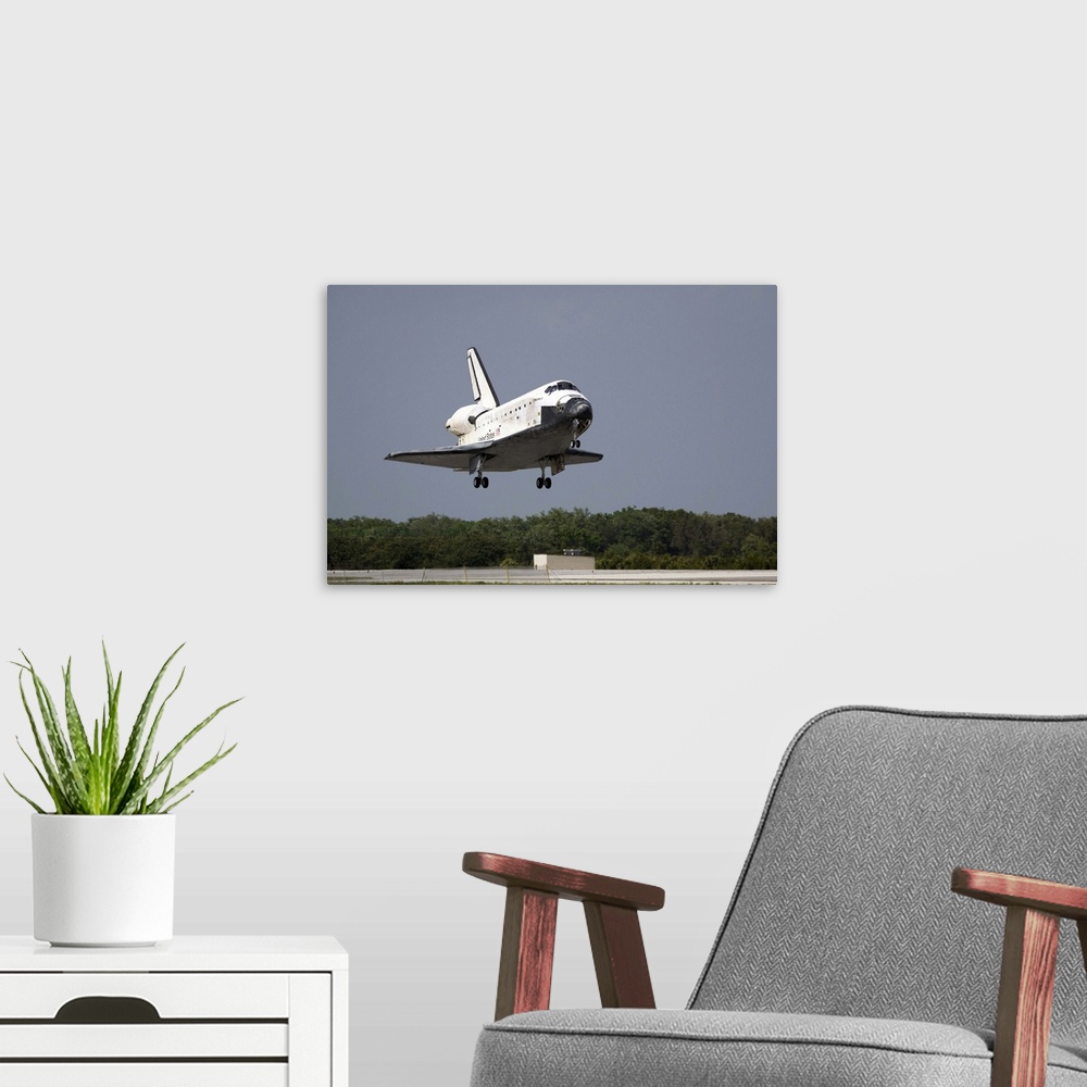 A modern room featuring Space Shuttle Discovery approaches landing on the runway at the Kennedy Space Center