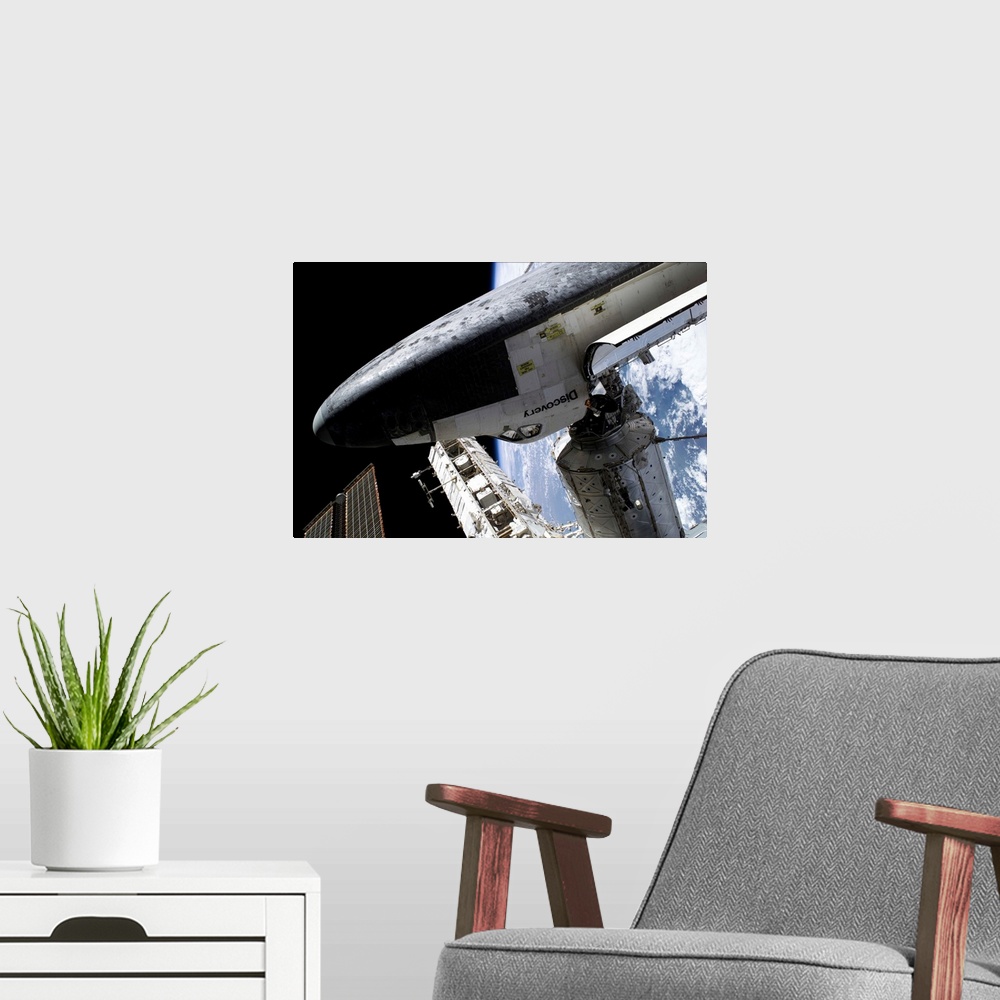 A modern room featuring Space Shuttle Discovery docked to the International Space Station