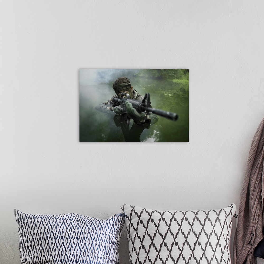 A bohemian room featuring Special operations forces soldier transits the water armed with an assault rifle.