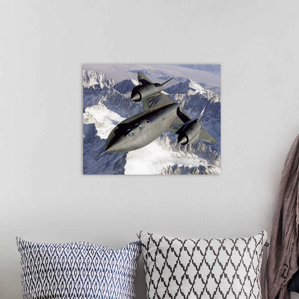 A bohemian room featuring A Lockheed SR-71 Blackbird spy plane flies over a mountain range as the sun shines down.