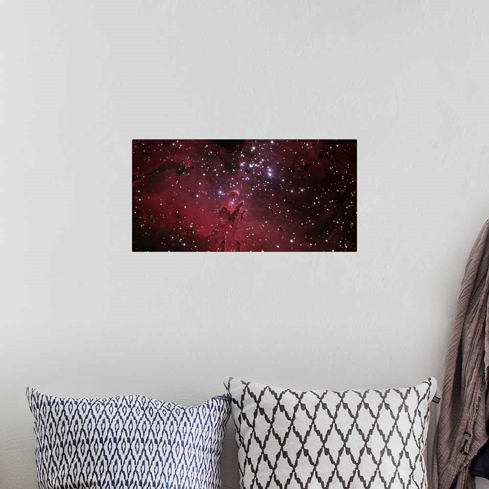 A bohemian room featuring An oversized piece of the eagle nebula that has bright stars scattered across the print with a re...