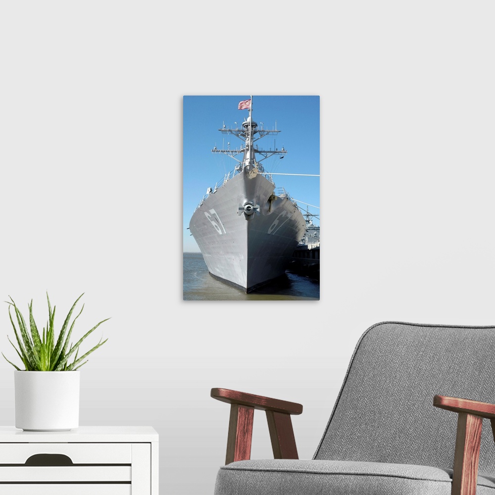 A modern room featuring The guided missile destroyer USS Cole sits moored to a pier