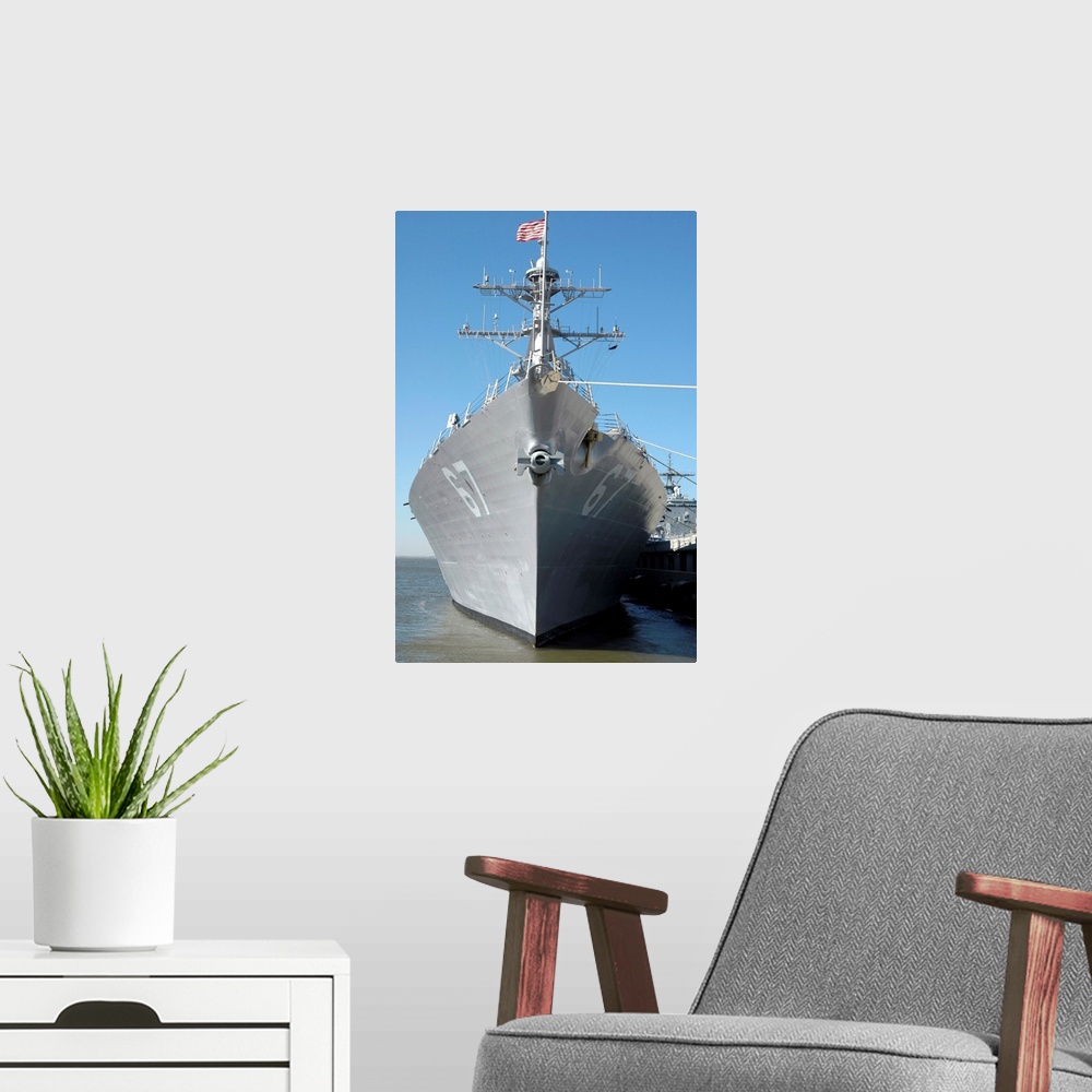 A modern room featuring The guided missile destroyer USS Cole sits moored to a pier