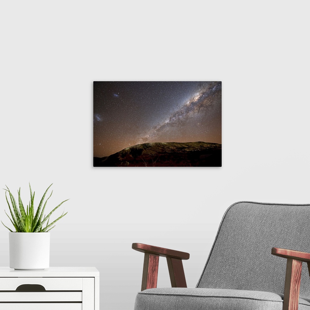 A modern room featuring The Milky Way and its satellite galaxies the Magellanic Clouds rising above the hills of Azul, Ar...