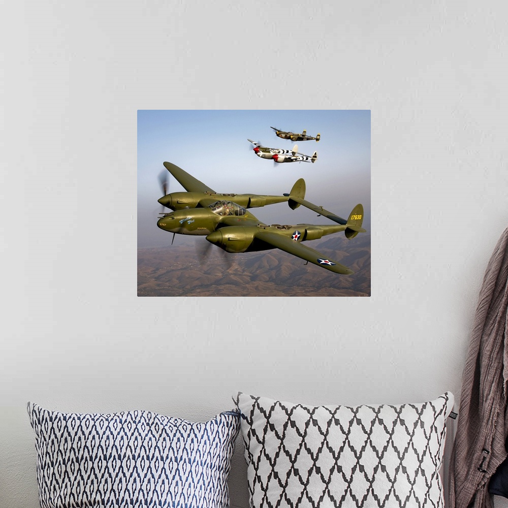 A bohemian room featuring Three vintage military aircrafts are photographed in the sky as they fly high over mountainous te...