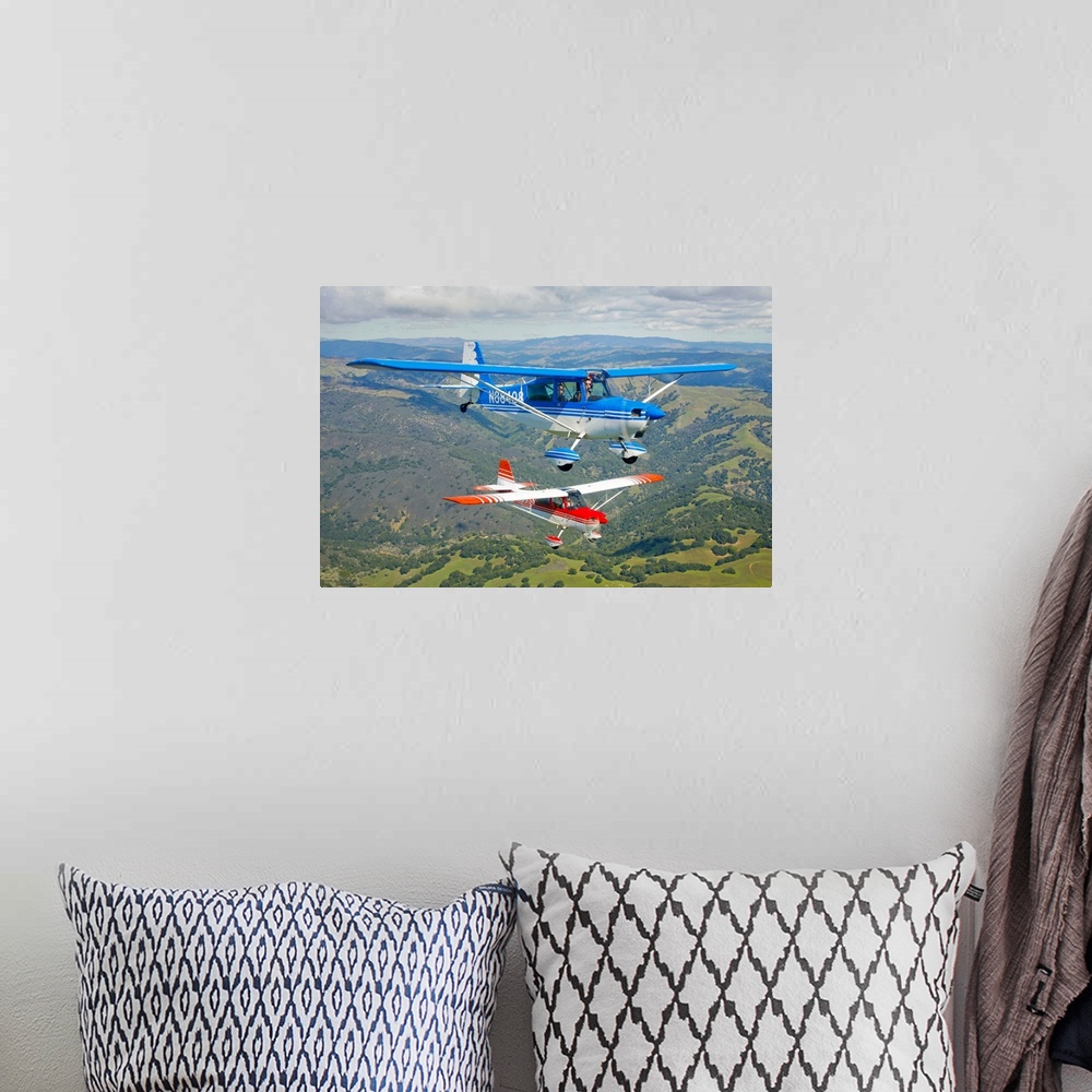 A bohemian room featuring Two small airplanes are photographed while in flight over vast open land.