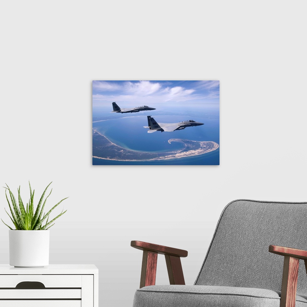 A modern room featuring Two F-15 Eagles from the Massachusetts Air National Guard fly high over Cape Cod during a trainin...