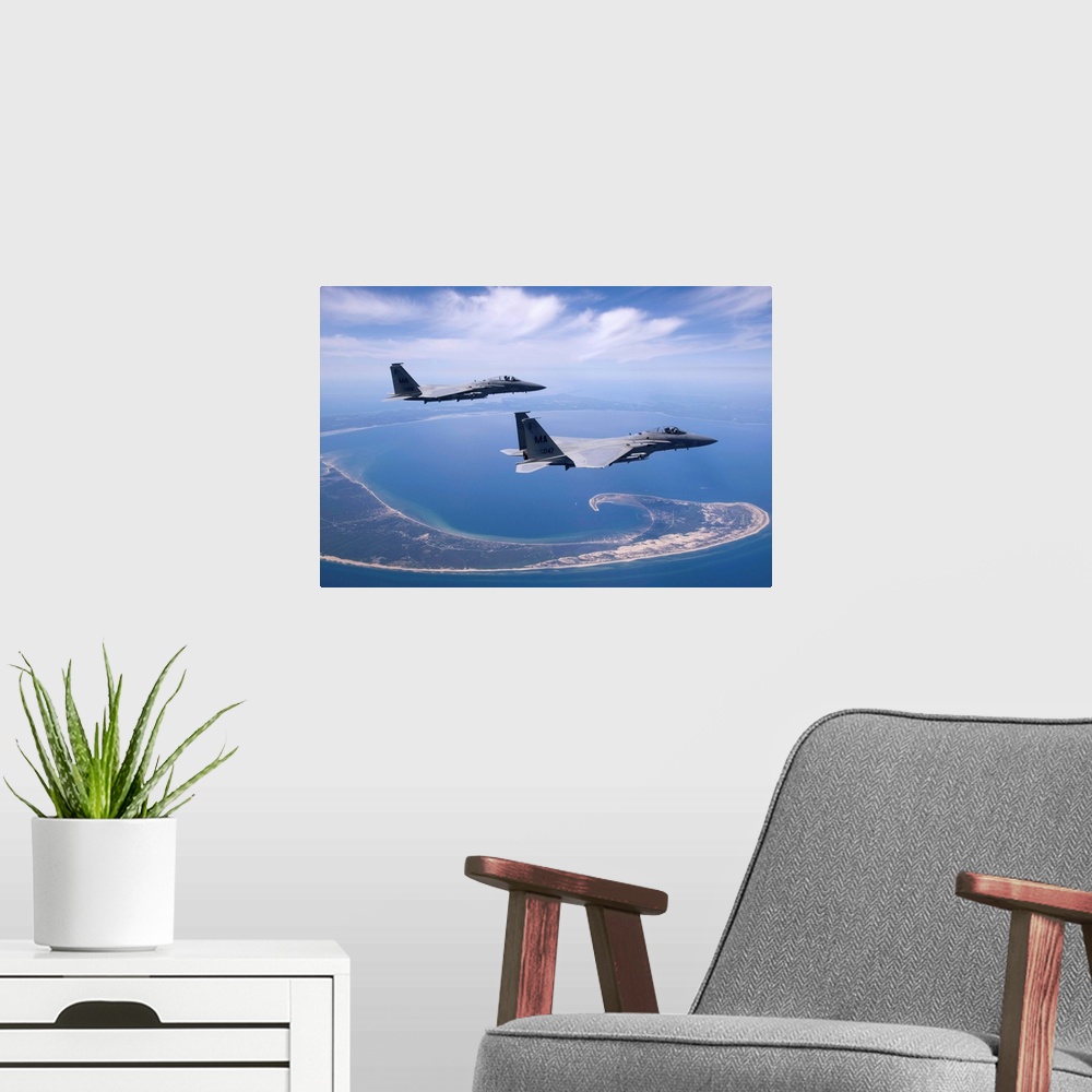 A modern room featuring Two F-15 Eagles from the Massachusetts Air National Guard fly high over Cape Cod during a trainin...
