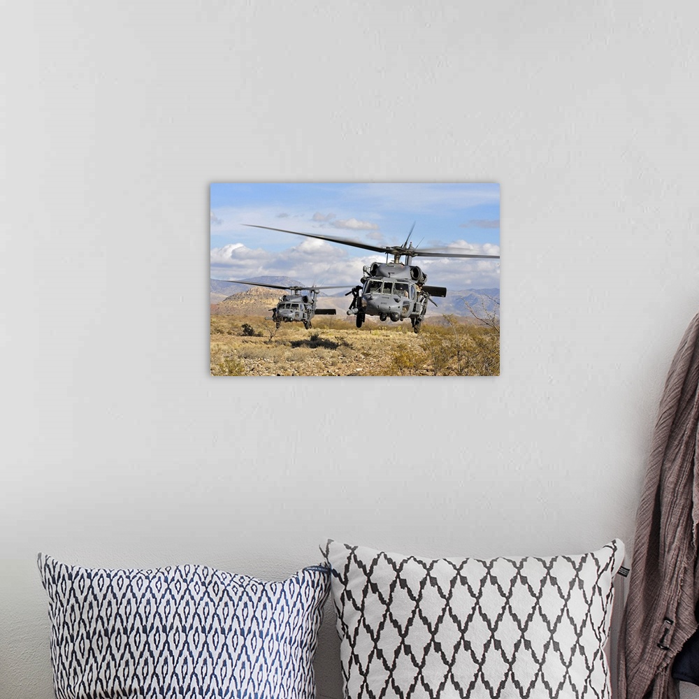 A bohemian room featuring A couple of military copters hovering a few feet off the ground in a desert during a training exe...