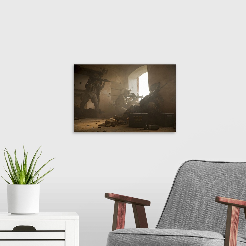 A modern room featuring This is a horizontal photograph of three soldiers in a damaged interior peering out a window.