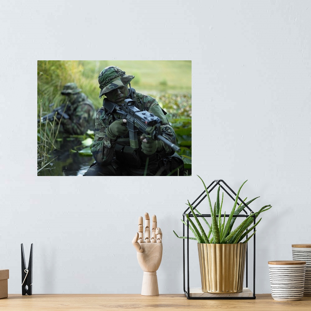 A bohemian room featuring U.S. Navy SEALs cross through a stream during combat operations.