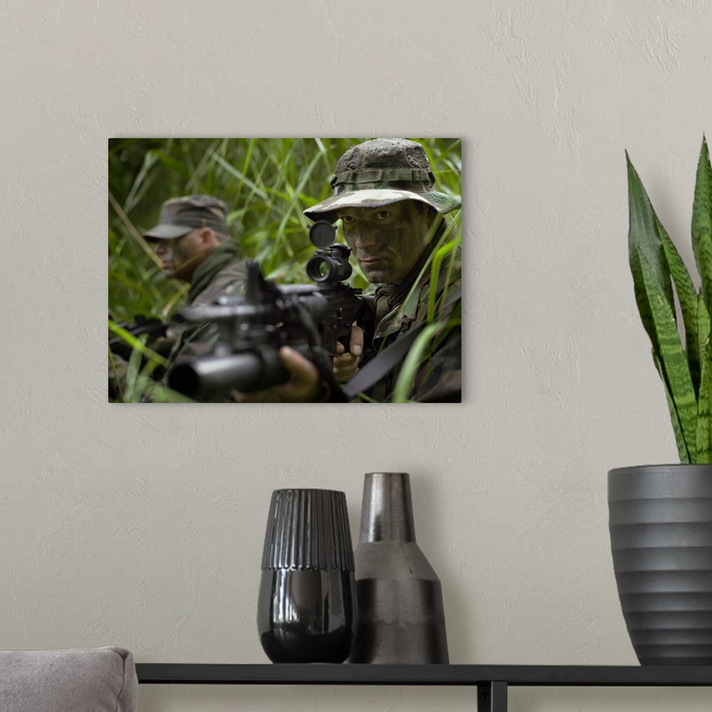 A modern room featuring U.S. Special Forces soldiers patrol through tall grass during combat.