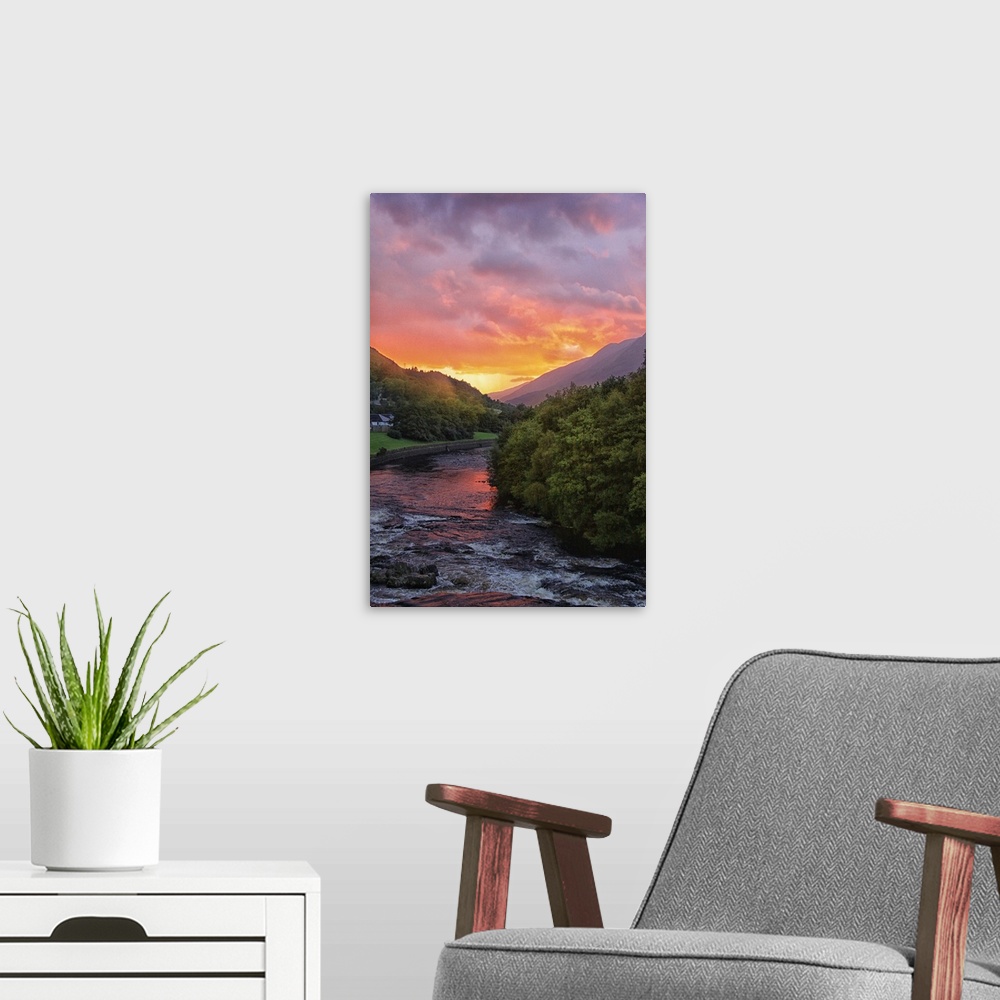 A modern room featuring Sunset illuminating the clouds over a river in Scotland.