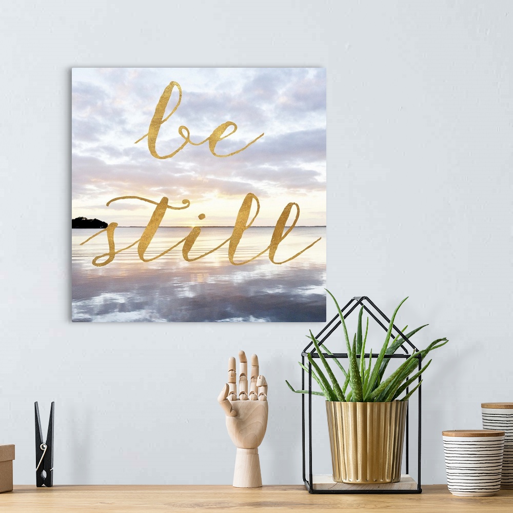 A bohemian room featuring "Be Still" hand written in gold letters over an image of the sea at dawn.