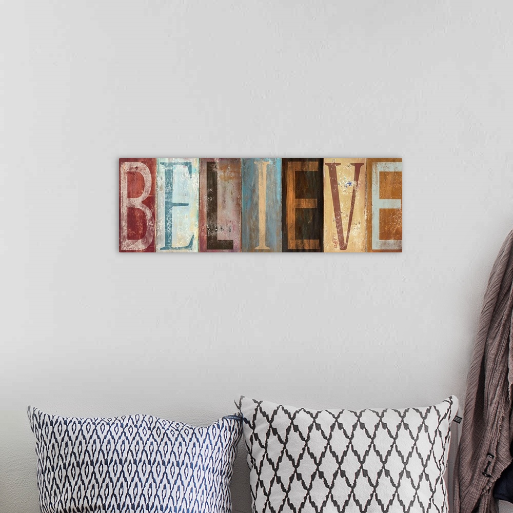 A bohemian room featuring The word "Believe" with each letter painted in a different style in muted colors, with a worn, we...