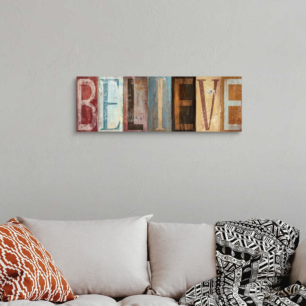 A bohemian room featuring The word "Believe" with each letter painted in a different style in muted colors, with a worn, we...