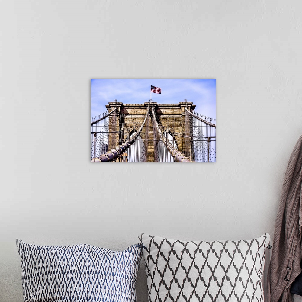 A bohemian room featuring An architectural photograph of the Brooklyn Bridge with the American flag on top.