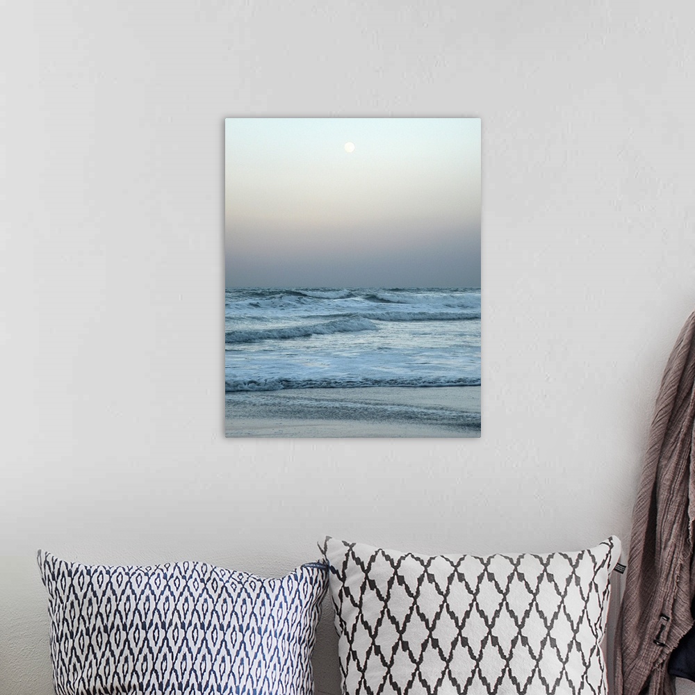 A bohemian room featuring A gray toned photograph of the ocean with a full moon.