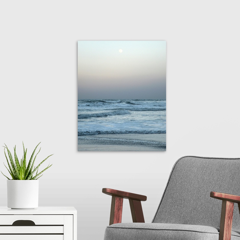 A modern room featuring A gray toned photograph of the ocean with a full moon.