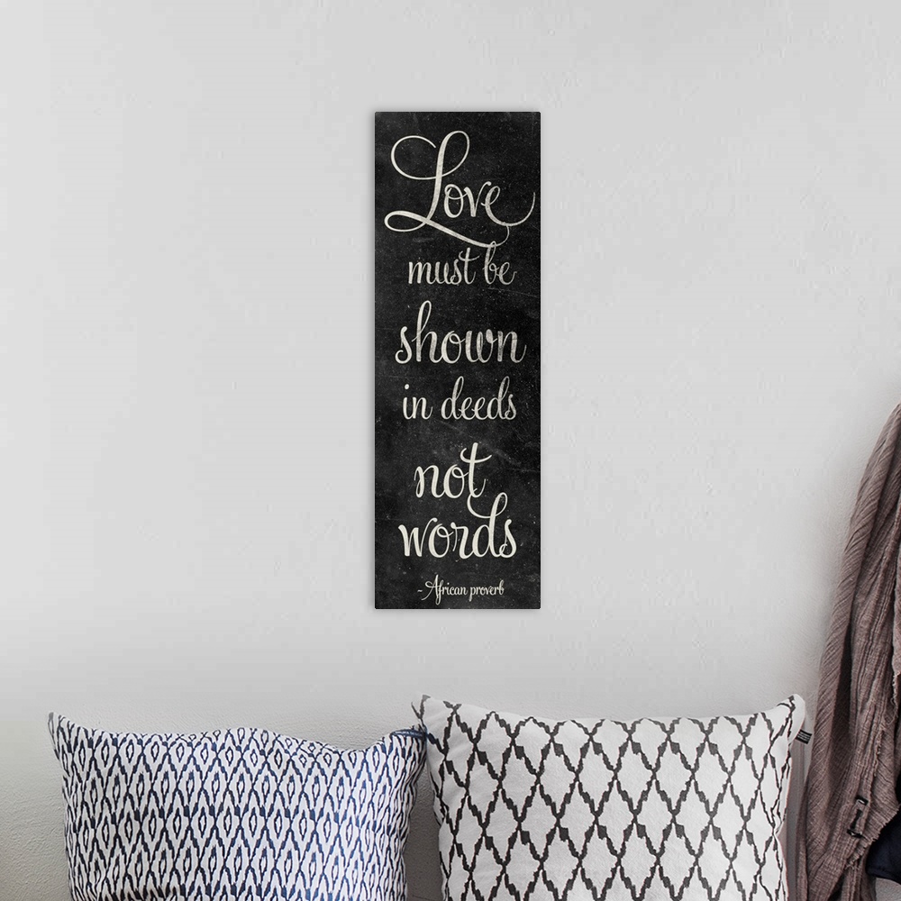 A bohemian room featuring "Love must be shown in deeds not words" in script writing on a chalkboard style panel.