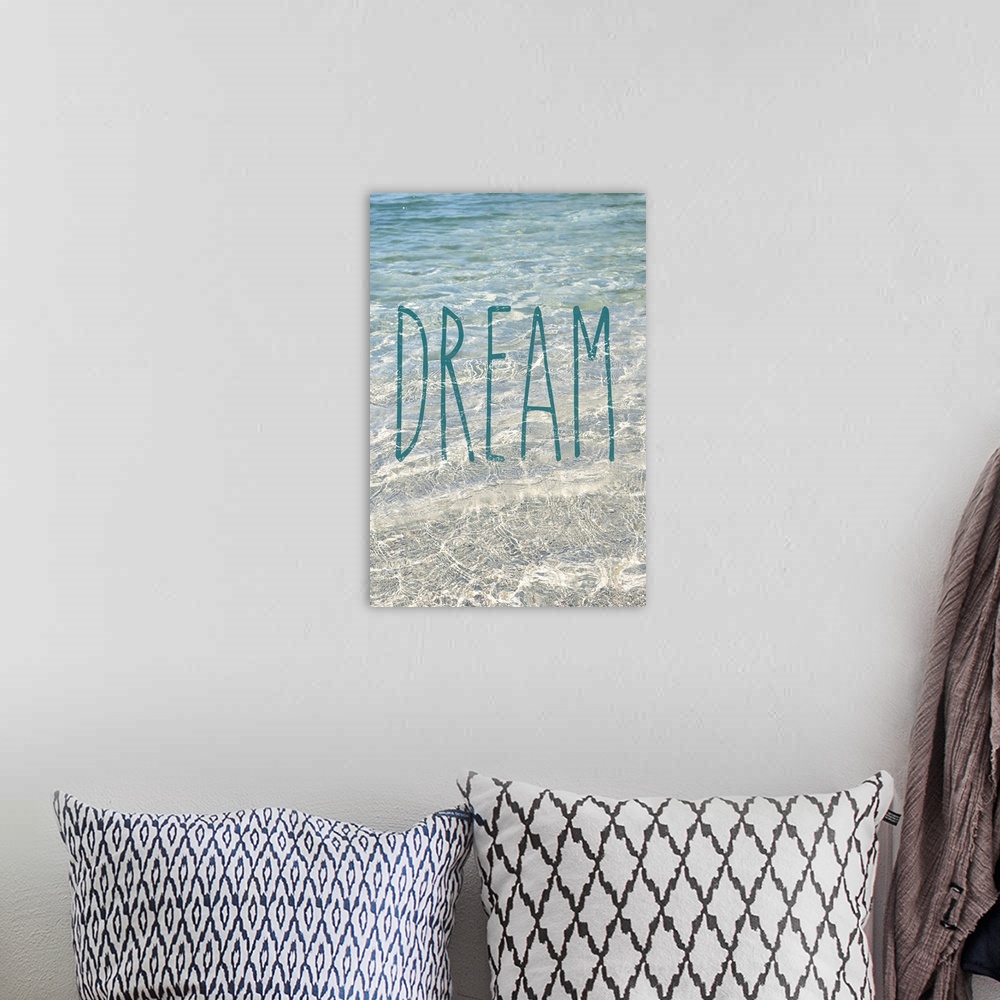 A bohemian room featuring "Dream" written in blue on top of a photograph of crystal clear ocean water.