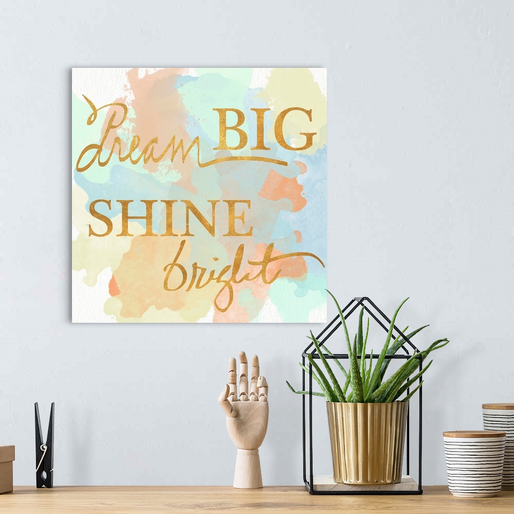 A bohemian room featuring "Dream Big Shine Bright" written in a shiny gold font on a pastel colored watercolor background.