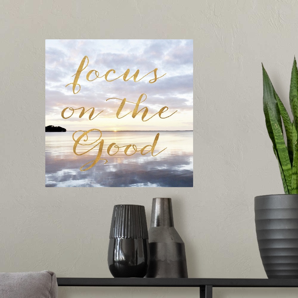 A modern room featuring "Focus on the good" hand written in gold letters over an image of the sea at dawn.