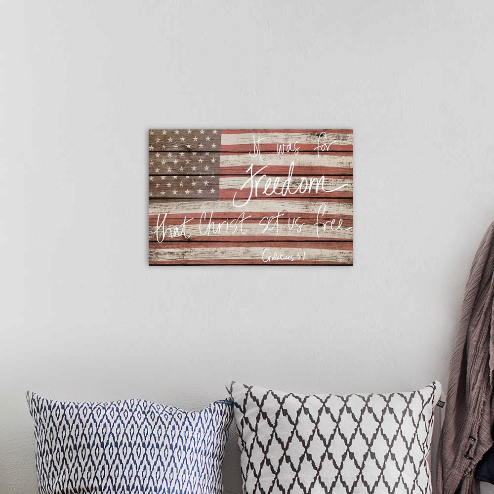 A bohemian room featuring American flag on wooden board with a bible verse handwritten over it.