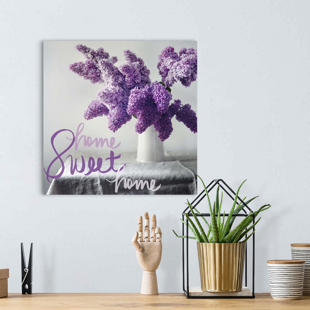 A bohemian room featuring A photograph of purple hydrangeas in a white vase on a table with the phrase "Home Sweet Home" wr...