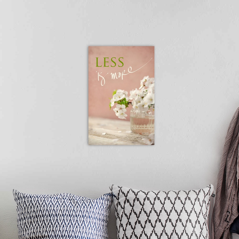 A bohemian room featuring Photograph of a white floral arrangement in a glass vase with the phrase "Less is More" written a...