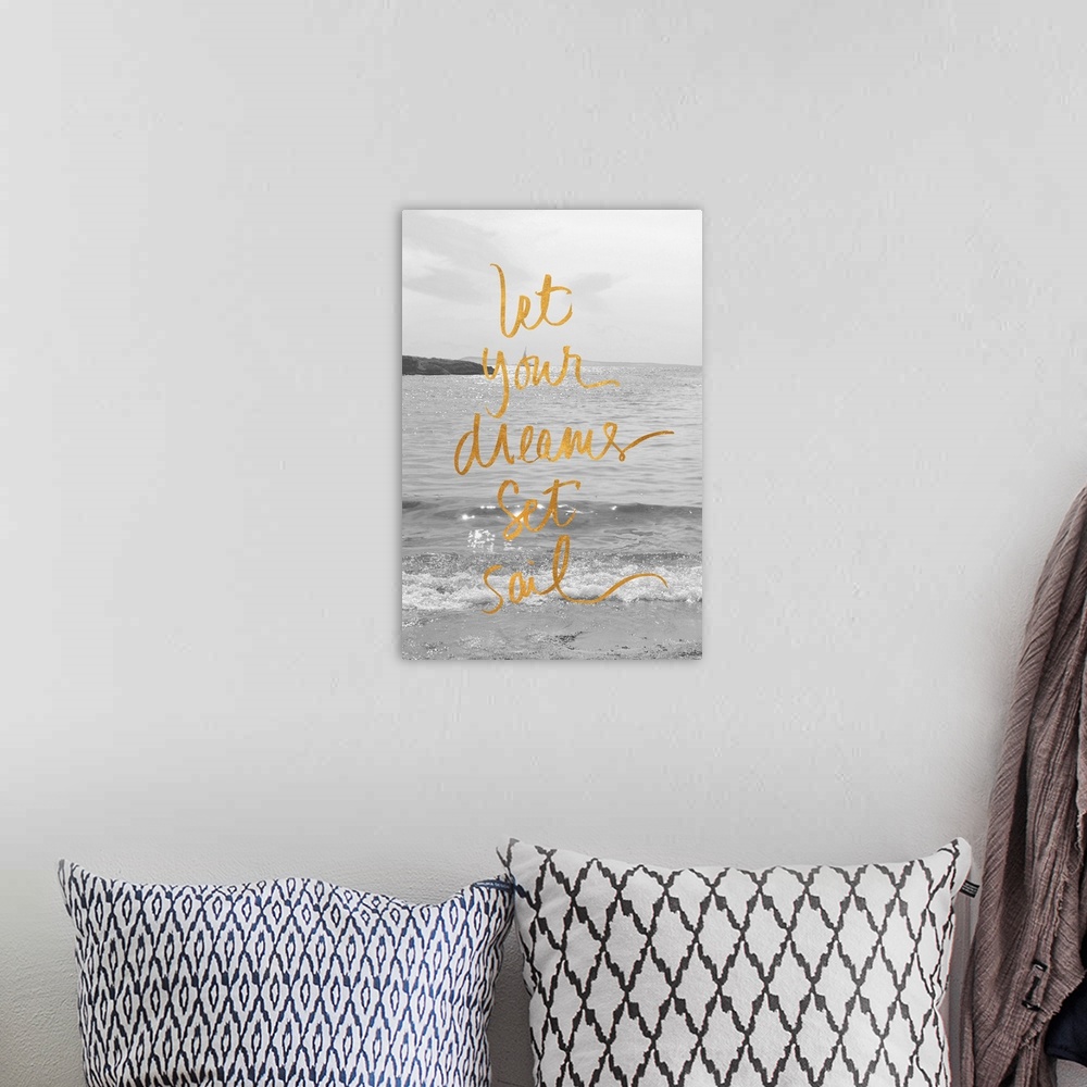 A bohemian room featuring "Let Your Dreams Set Sail" written in gold on top of a black and white photograph of the ocean wi...