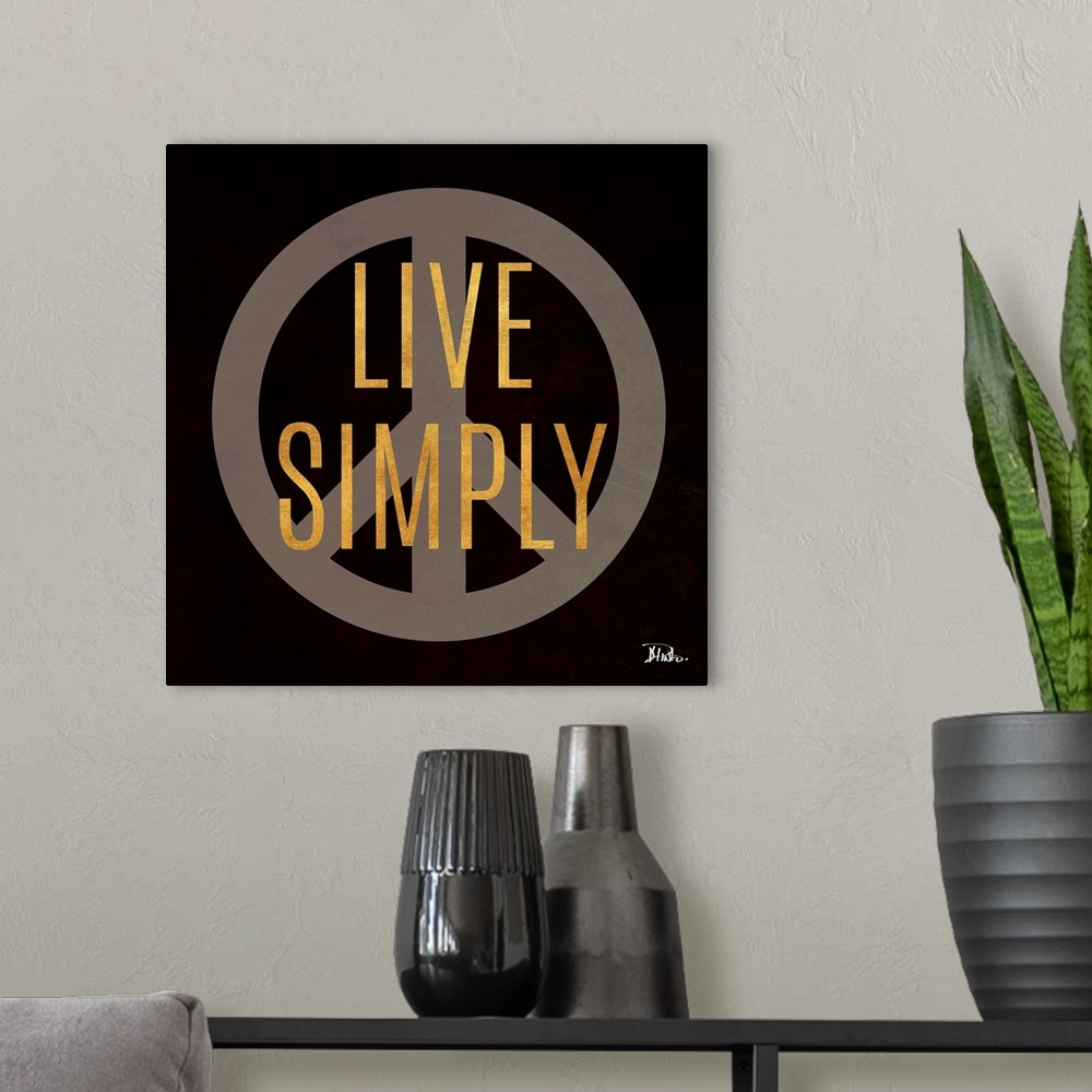 A modern room featuring The words "Live Simply" in gold over a peace sign against a black background.