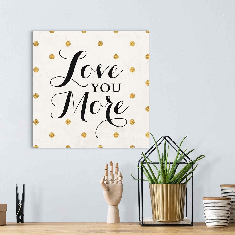 A bohemian room featuring The words "Love You More" in black script on a cream background with gold dots.