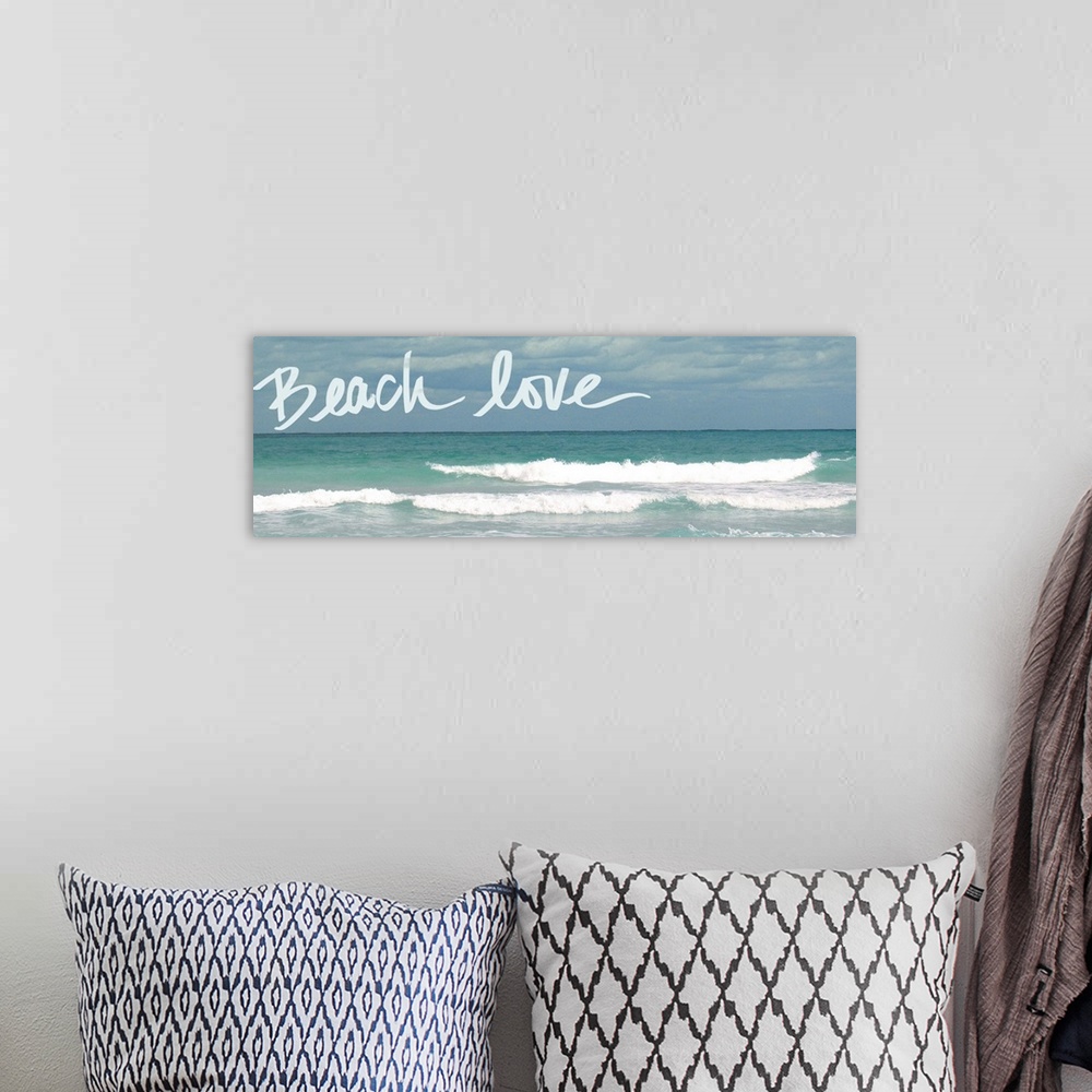 A bohemian room featuring Horizontal photograph of rolling waves in the ocean with "Beach love" handwritten in the sky.