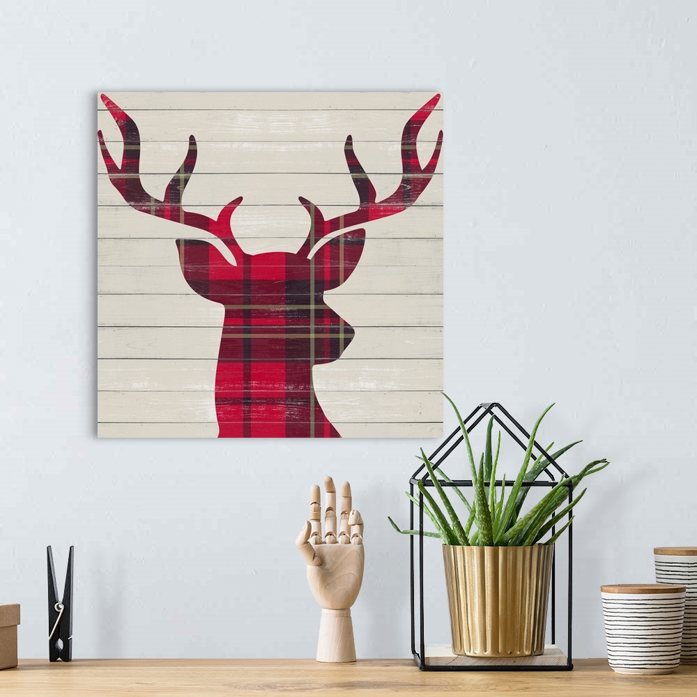 A bohemian room featuring A red plaid silhouette of a deer on a wood paneled background.