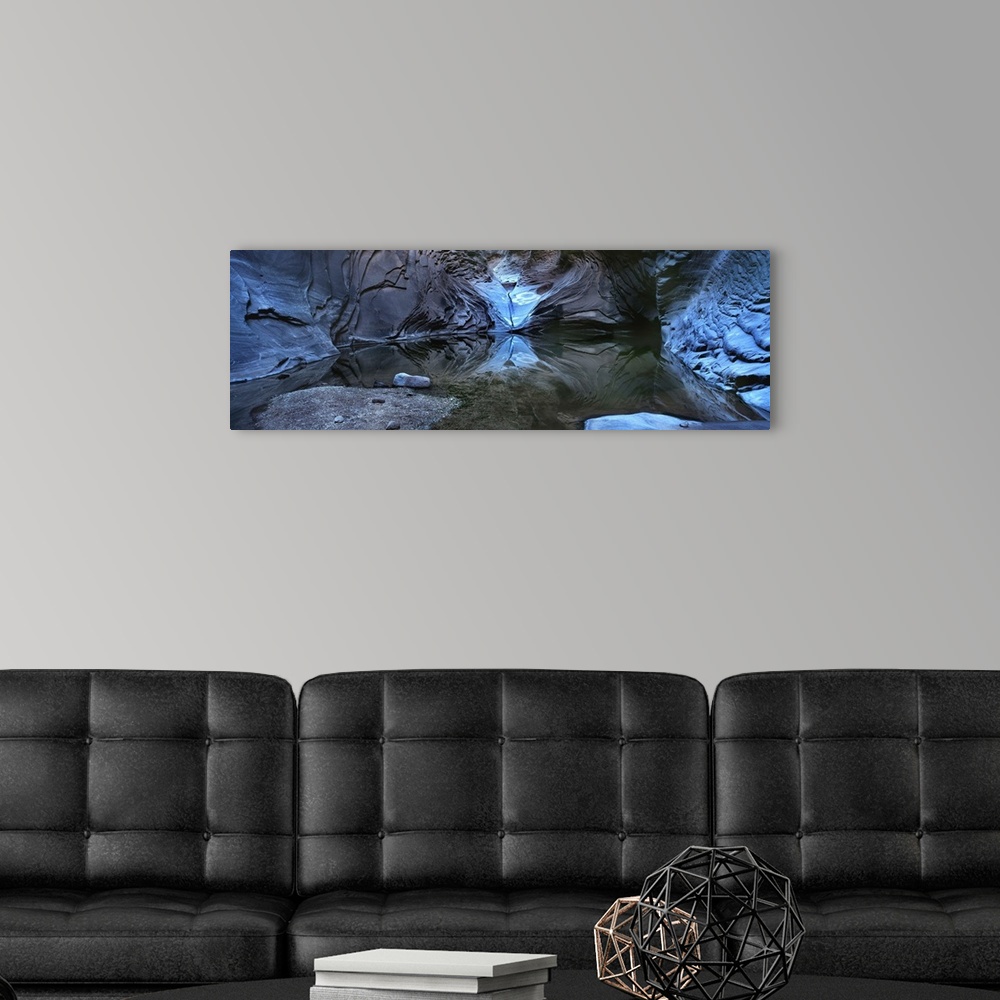 A modern room featuring Photograph of a cave illuminated in blue with still water reflecting all the rocks around.