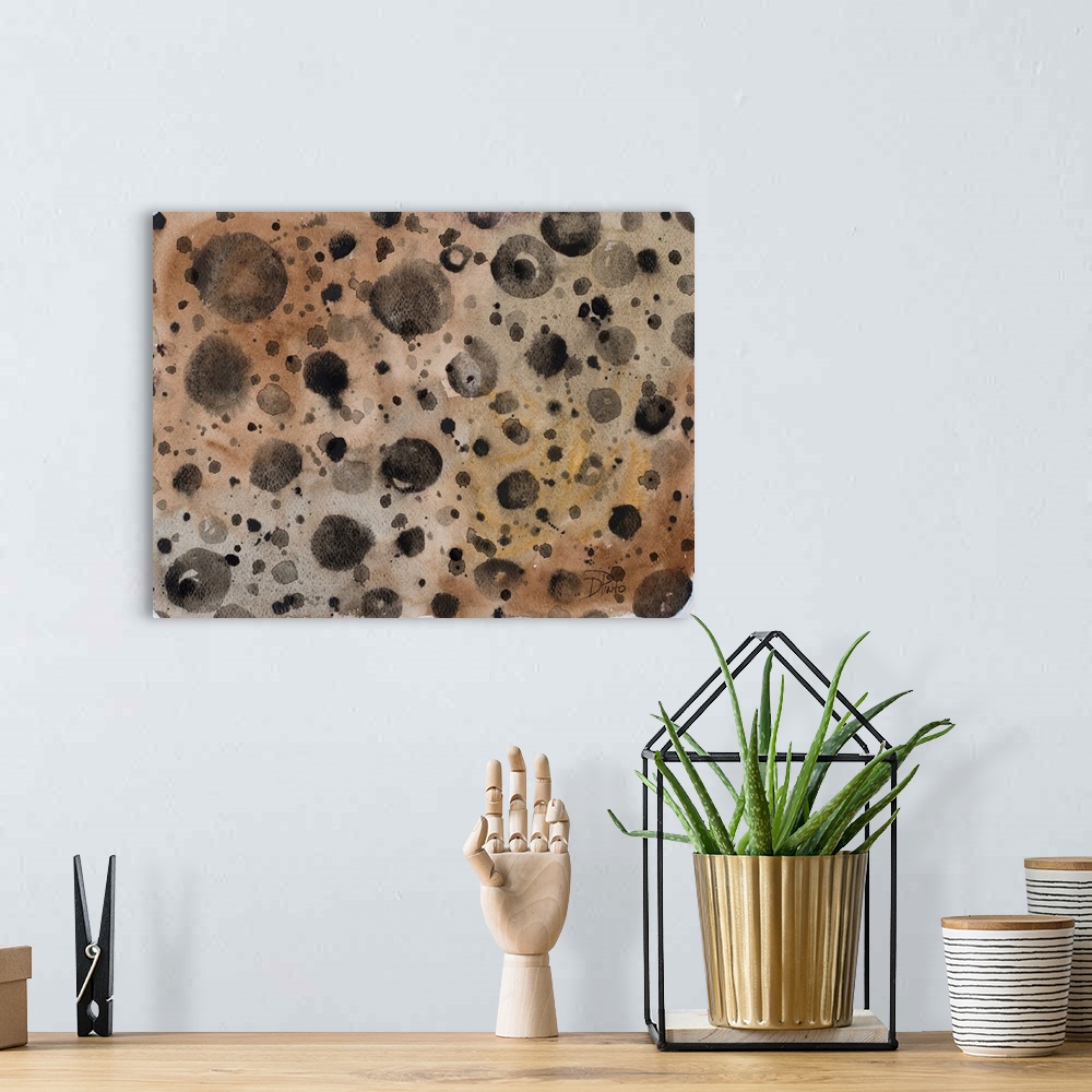 A bohemian room featuring A patterned watercolor painting with black paint splatter on a brown background with hints of gold.