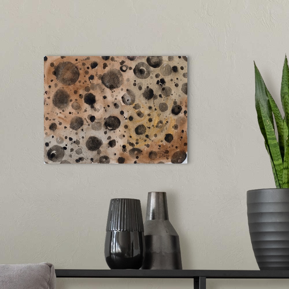 A modern room featuring A patterned watercolor painting with black paint splatter on a brown background with hints of gold.