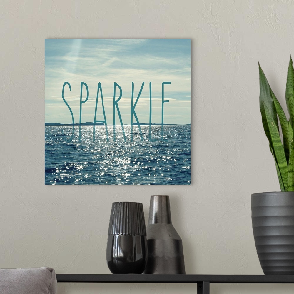 A modern room featuring A beautiful blue and gray toned square photograph of the ocean water with the sun shining down on...